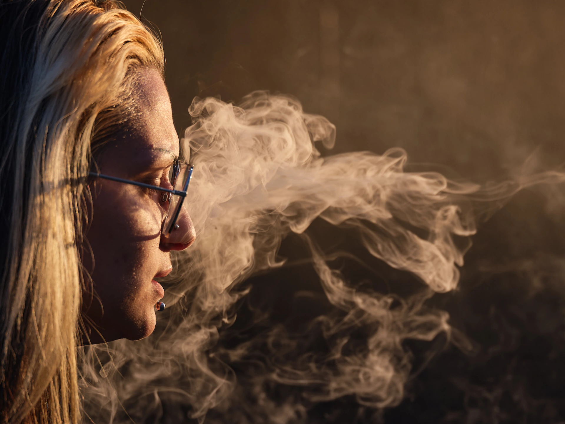 Macro technical portrait by San Francisco photographer; detailed side profile of a woman with smoke backlighting during golden hour, captured on GFX medium format for high-fidelity texture.
